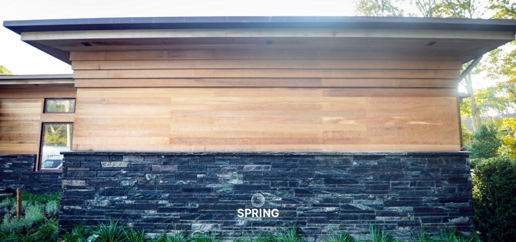 Architectural detail of The Sound House in Sag Harbor, displaying a blend of glass, wood, and stone, emphasizing eco-luxury living.